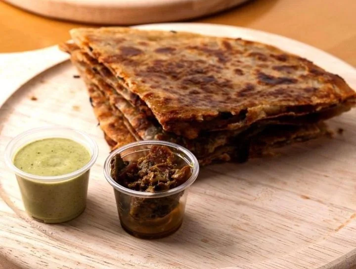 Aloo paratha served with dipping sauces