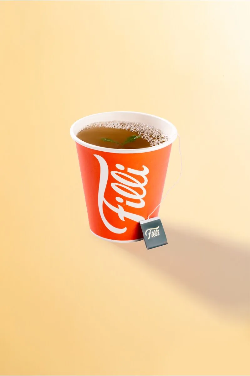 Orange FiLLi cup of amber tea with a tea bag tag
