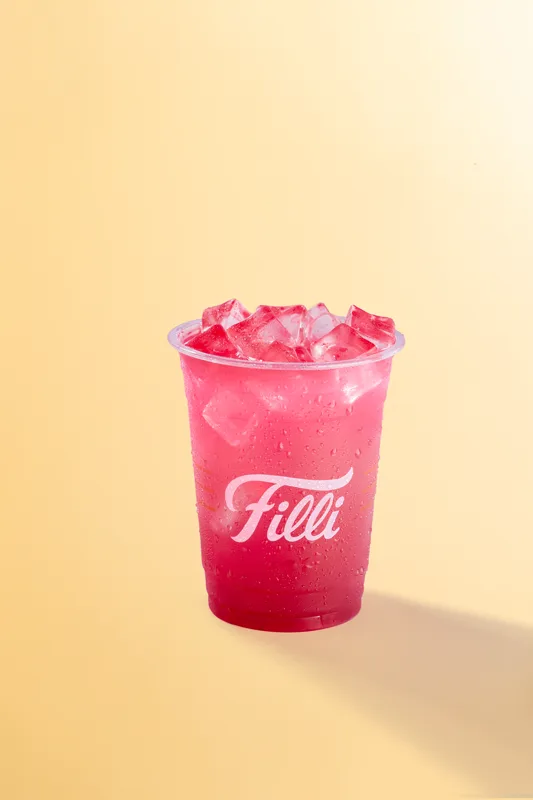 Clear FiLLi cup of bright pink mango dragonfruit drink over ice