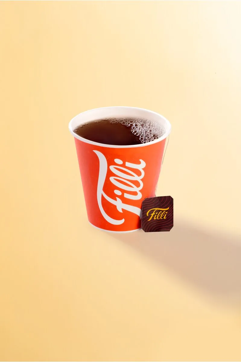 Orange FiLLi cup of black tea with a tea bag tag