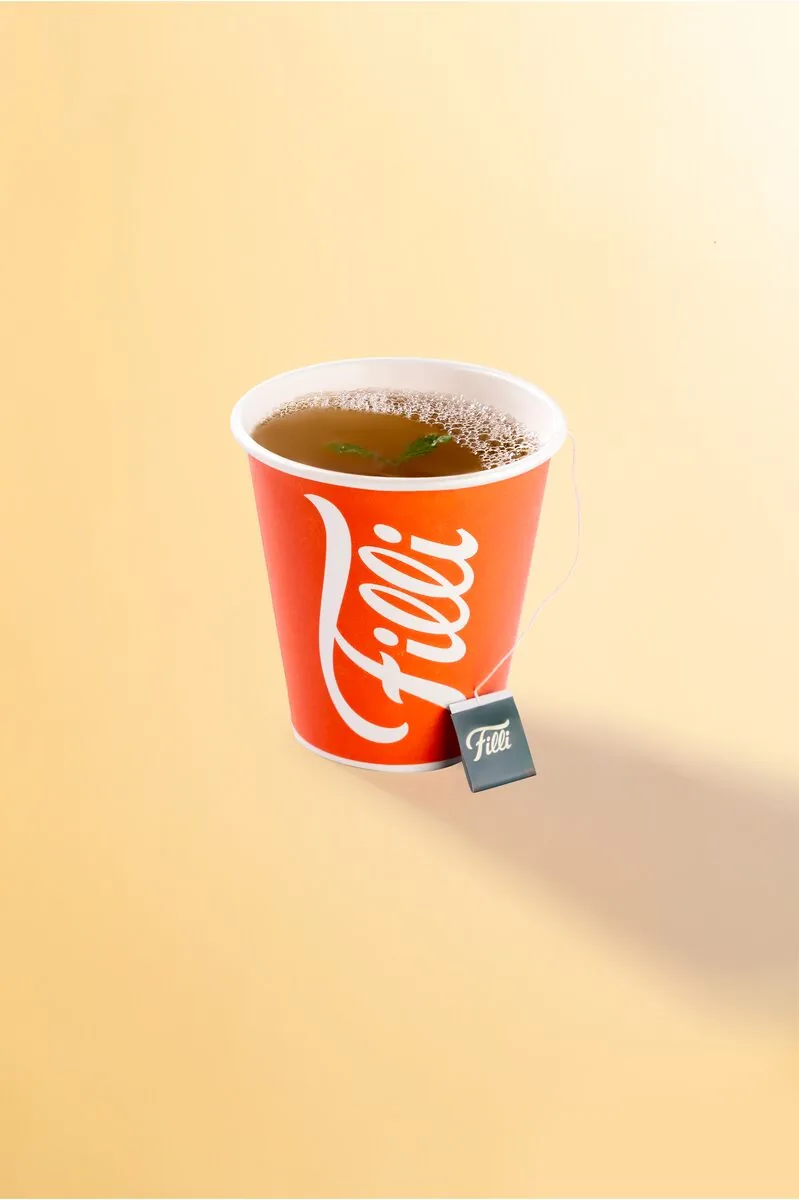 Orange FiLLi cup of amber tea with a tea bag tag