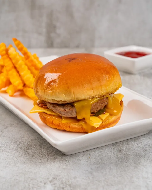 Old fashioned beef burger with melted cheese served with crinkle fries