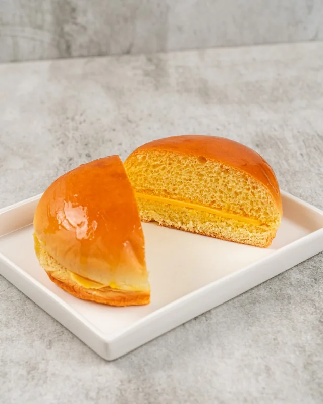 Two halves of a glazed Bun Maska on a white plate